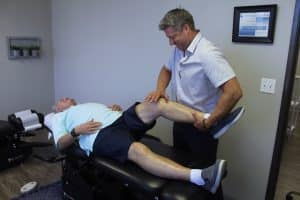 Dr. Michael Bell assesses and adjusts a patient's knee to relieve knee pain.