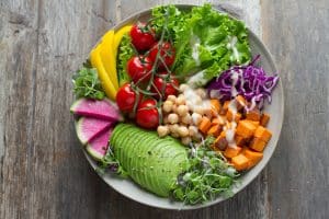 A gray bowl full of brightly colored vegetables for a well-balanced meal nourishes the body and helps sustain a gut health.