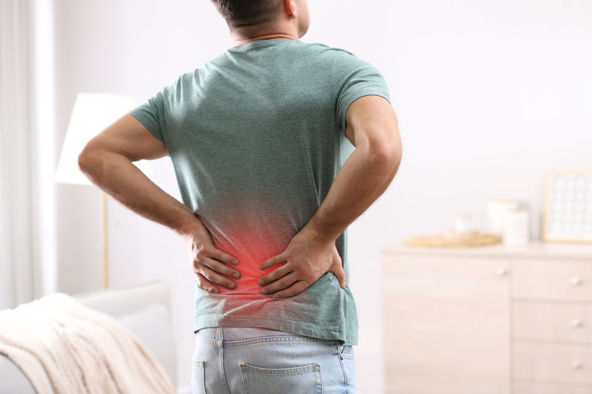 A man with back pain holding his lower back.