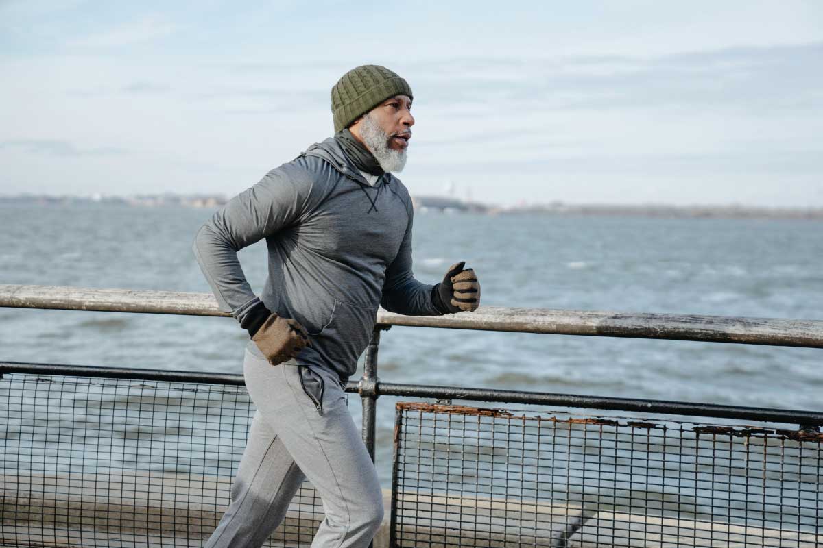 Embrace Aging with Grace: How Functional Medicine Can Help 2 A healthy and fit older man going on a jog by a lake.